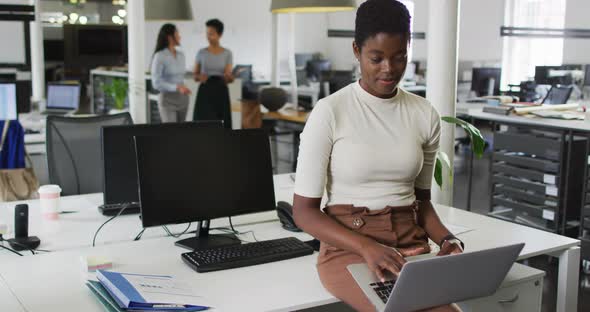 Smiling african american businesswoman working on laptop in office