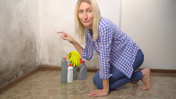 The woman is upset about the appearance of new mold on the wall.