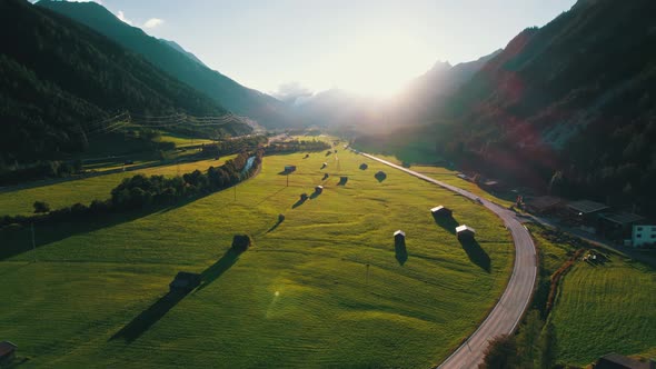 Aerial View of Empty Road in Austrian Valley Between Green Fields at Sunset Alps