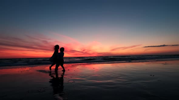 Happy Kids Play on the Beach at Sunset