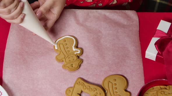 Woman in Red New Years Pajamas Is Icing a Traditional Gingerbread Cookie