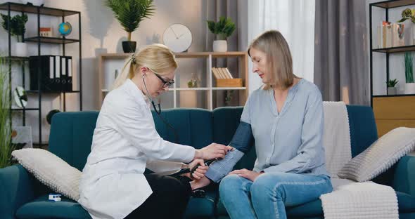 Doctor Measuring Blood Pressure at Middle-Aged Sick Woman Using Tonometer