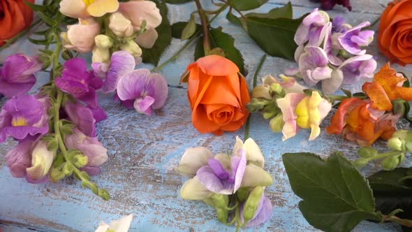 Colorful summer garden flowers: dragon flowers, roses, sweet pea on the vintage wooden