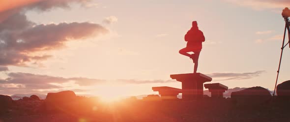 Man stands in yoga posture during sunset