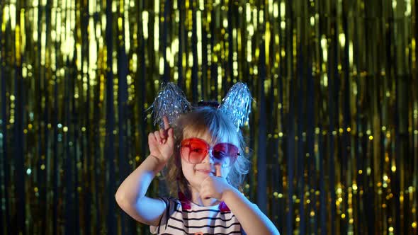 Trendy Girl in Stylish Glasses Standing on Blue Neon Lights Pointing at Blank Space Agree Sign