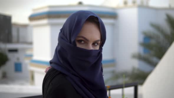 Young Woman in Arabic Burqa. A Woman Is Looking at the Camera. Against the Background of the Arab