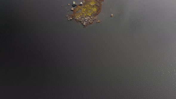 Aerial footage of remote lake in northern Maine flying over a small rocky island.