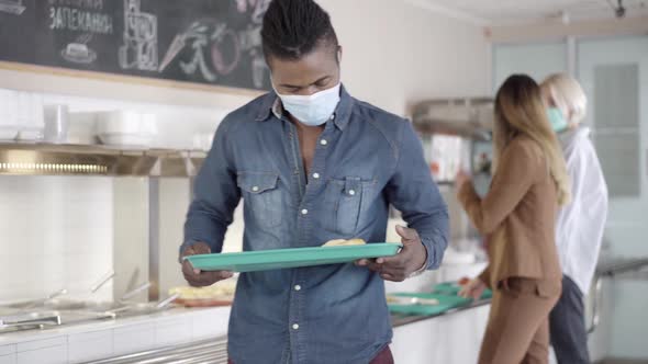 Young Confident African American Man in Covid Face Mask Turning To Camera with Tray of Ukrainian