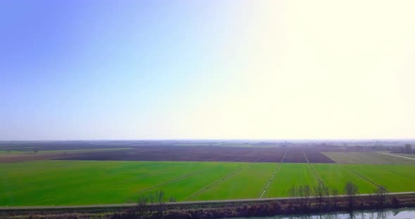 Channel By Asphalt Road Against Boundless Fresh Green Field