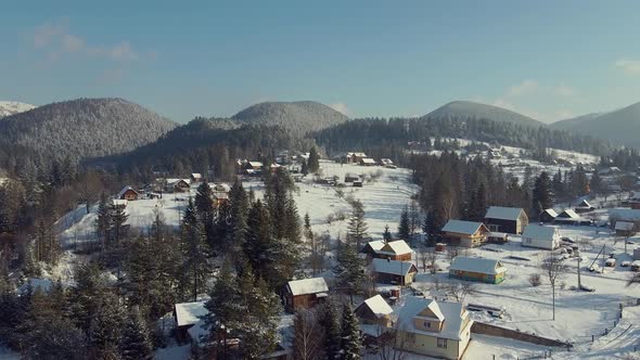 Scenic Landscape of Snowy Hills with Private Houses and Mountains in the Background