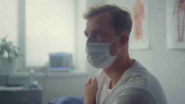 Tired Patient Sitting Wearing Mask in Clinic Closeup