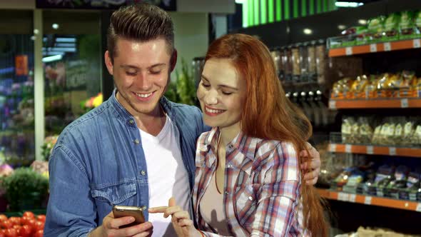 Couple Uses Smartphone at the Hypermarket