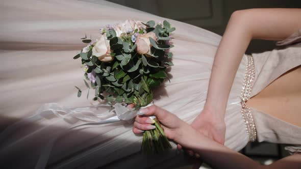 A Girl in a Beige Dress Holds a Beautiful Bouquet Behind Her Back