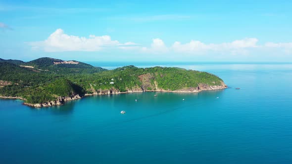 Tropical island with rainforest green hills surrounded by blue sea on a summer day with bright sky a