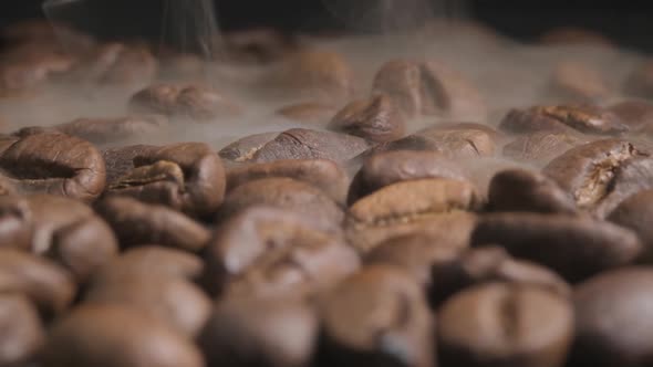 Slow motion macro shot of freshly roasted coffee beans, aromatic smoke coming from the beans as they