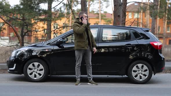 A man walks near a broken car alt