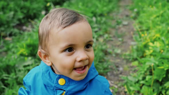 Portrait of Adorable Baby Boy Smiling and Laughing on Green Forest Background. Cute Kid in Blue