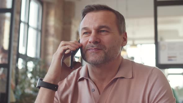 Mid-Age Businessman Talking on Cell Phone in Office