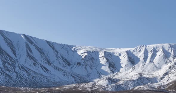 Timelapse of Sun Movement on Crystal Clear Sky Over Snow Mountain Top. Yellow Grass at Autumn Meadow