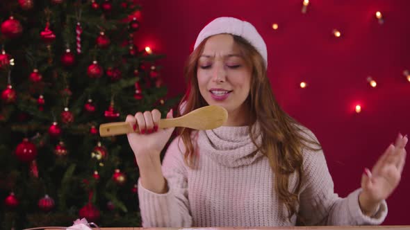 Young Pretty Woman Have Fun on Christmas Kitchen, Sings Xmas Songs Using Spatula