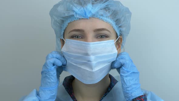 Happy smiling female scientist taking off protective medical face mask after coronavirus pandemic