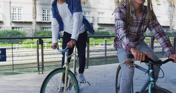 Two diverse male friends riding bicycles in street