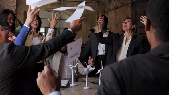 Multiethnic business people celebrate renewable energy project success throwing documents at office