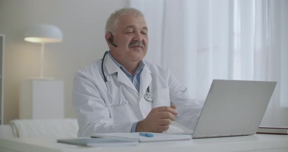 Kind Cheerful Doctor Is Consulting Online, Working By Internet with Patient, Chatting By Video Call