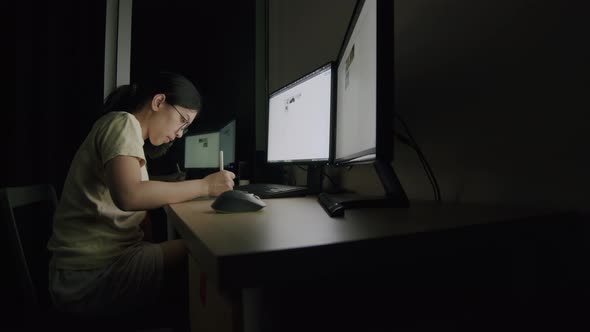 Asian businesswoman writes an article on a tablet at night in a home office.