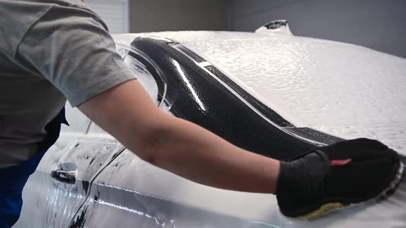 Close Up Male Hand in Black Glove with Foam Sponge Washing Car Roof. Concept: Auto Car Service, Car