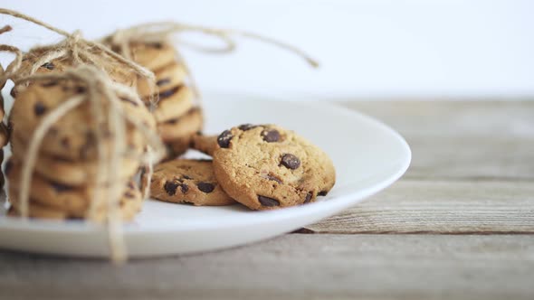 The Hand Takes The Pastry Biscuits. A Beautiful Cookie Lies On A White Plate. Textured Wooden Table.