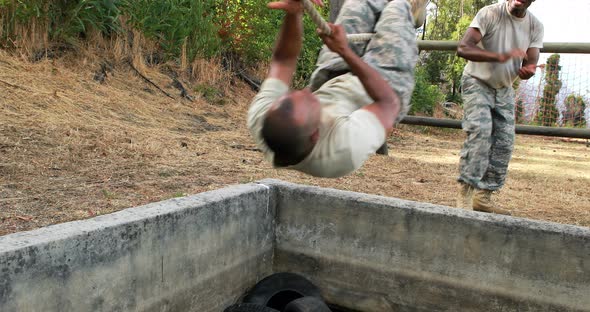 Military soldier climbing rope during obstacle course