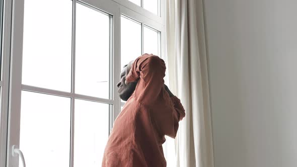 African American Man Wakes Up and Stretches Standing at the Window in the Early Morning Before