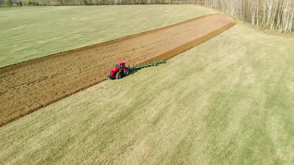 Aerial Photography of a Tractor with a Trailing Plow in Operation in the Field, Top View of Plowed