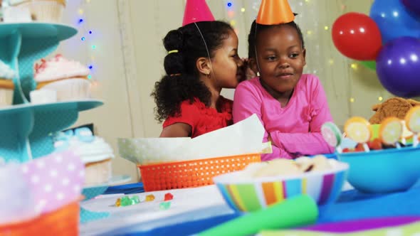 Girl whispering secret to her friend during birthday party 4k