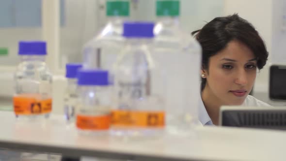 Female scientist working on computer and looks at screen in laboratory