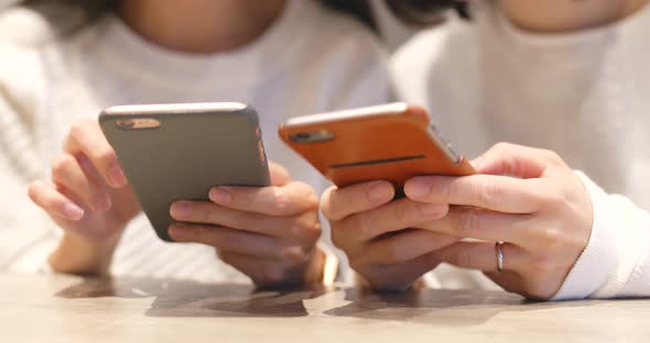 Friend using cellphone together in restaurant