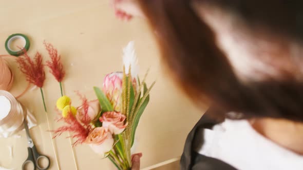 Florist Making Bouquet of Roses Adding Dried Flowers at Workplace