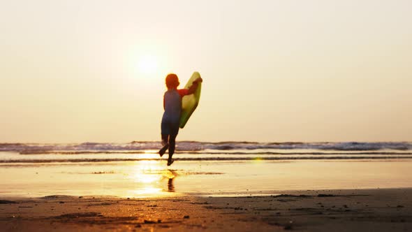 Little Girl Is Running on the Sea To Waves Holding Surfboard in Her Hands.