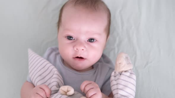 Newborn Baby Boy 3 Months Old Lies in Crib Nursery with Blue Clothes on His Back with Teddy Bear