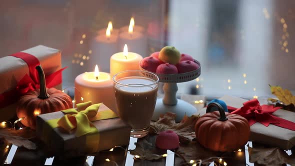 cup of coffee or tea near a pumpkin, gifts and candles