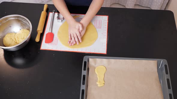 Unrecognizable Boy Cuts a Christmas Tree Out of Dough Using a Shape