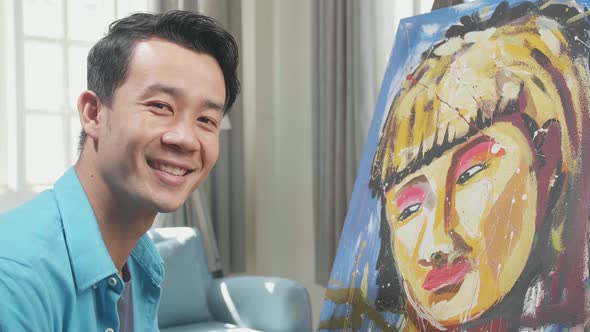 Asian Artist Man Holding Paintbrush Mixed Colour Turn To Smile While Painting