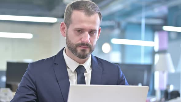 Portrait of Serious Businessman Working on Laptop