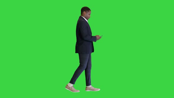 Young African American Man Walking and Texting on a Green Screen Chroma Key