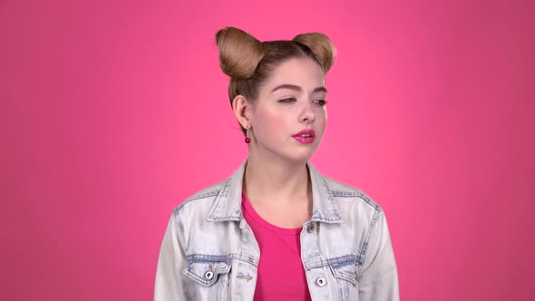 Girl Begins To Smile at the Camera. Pink Background. Close Up. Slow Motion