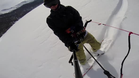 A young man snow kiting on a snowboard.