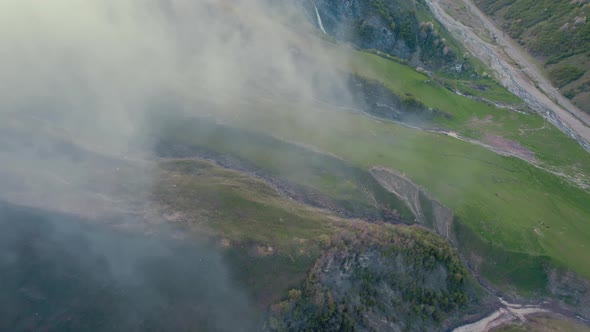 Topdown View of Caucasus Mountains Slope Covered with Clouds and Old Military Road in Distance