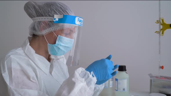 Doctor wearing protective clothing, looking at blood sample