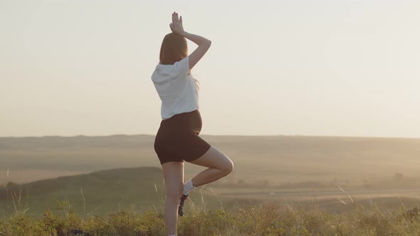 Young Pregnant Woman Stands in Yoga Pose in Open Air Background the Sky Side View